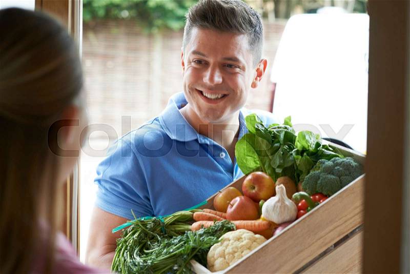 Man Making Home Delivery Of Organic Vegetable Box, stock photo