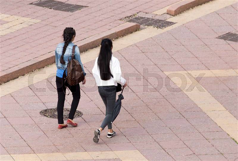 Two girl is walking along paving stones , stock photo