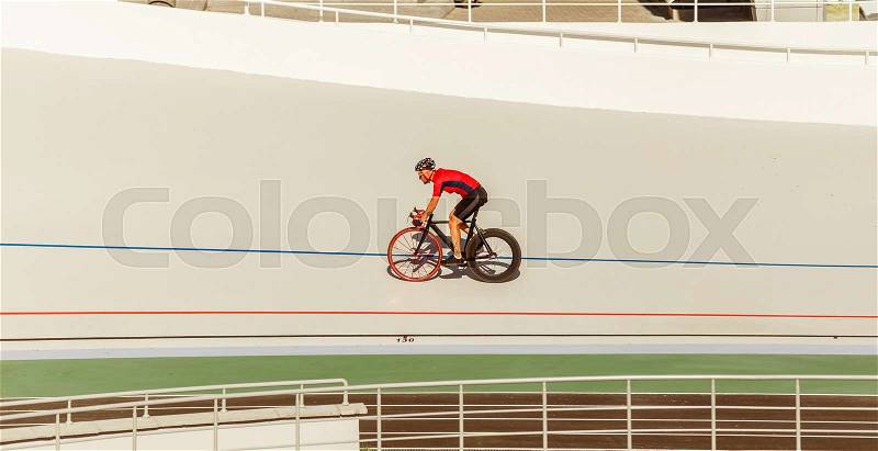 Bicyclist on cycle track outdoor. Active man racing at white velodrome, stock photo