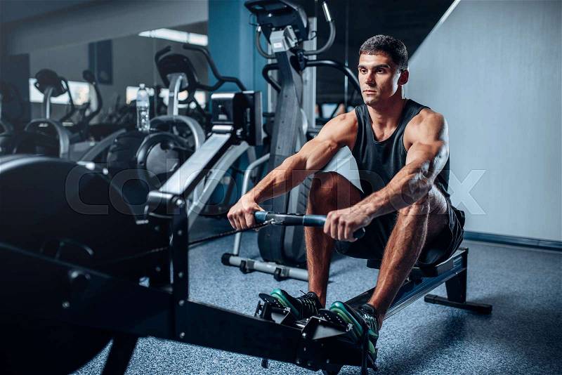 Muscular athlete training press on exercise machine. Active sport exercises in gym, stock photo