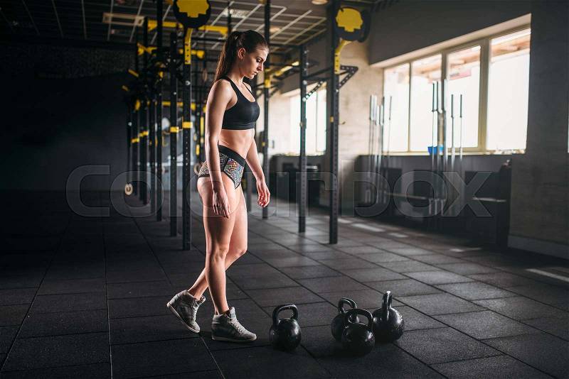 Slim woman posing with weight in fitness club. Attractive female athlete training in gym, stock photo