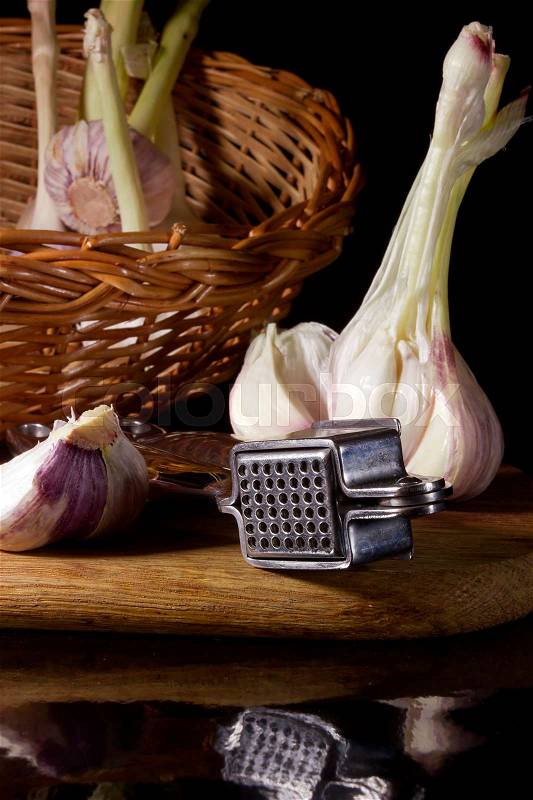 Garlic press and cloves of garlic laid on a wooden table background, stock photo
