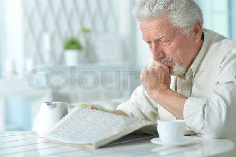 Portrait of an elderly man reading a newspaper, stock photo