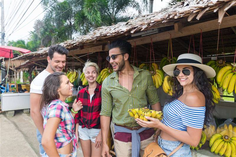 People Group Buying Bananas On Street Traditional Market, Young Man And Woman Travelers Choosing Fresh Fruits, stock photo