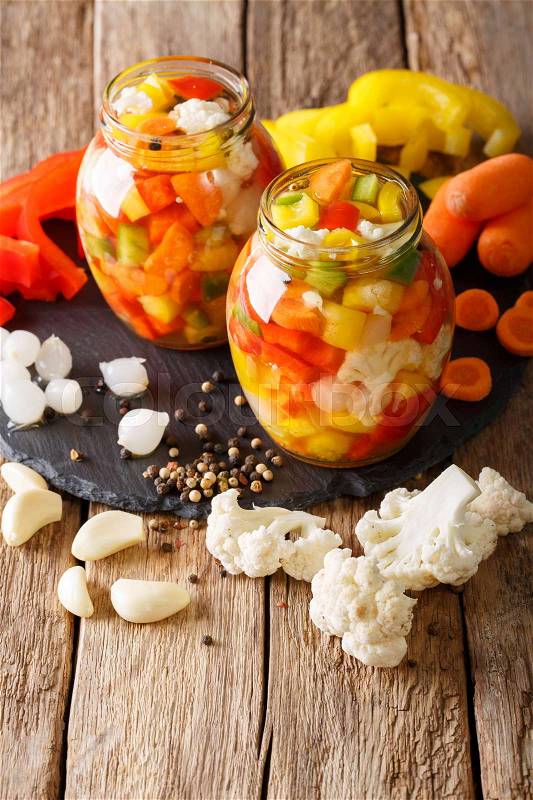 Italian Giardiniera salad of pickled cauliflower, pepper and carrots close-up in glass jars. Vertical , stock photo