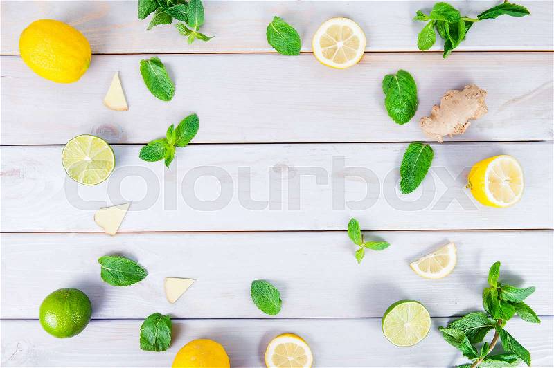 Colorful pattern of mint, lime, lemon,ginger slices. . Limes and Lemons sliced and whole with leaves. On white wooden background. Free space for text . Top view, stock photo