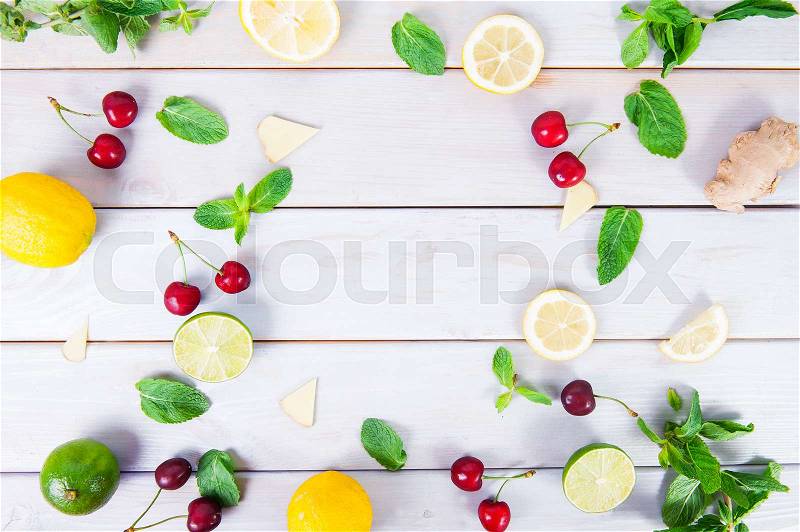 Colorful pattern of cherry, mint, lime, lemon,ginger slices. . Limes and Lemons sliced and whole with leaves. On white wooden background. Free space for text . Top view, stock photo