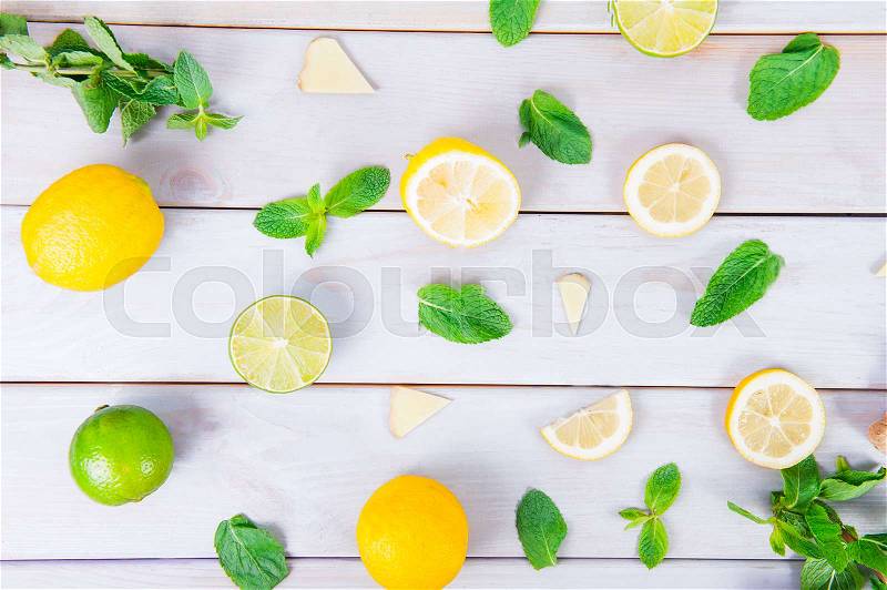 Colorful pattern of mint, lime, lemon,ginger slices. . Limes and Lemons sliced and whole with leaves. On white wooden background. Top view, stock photo