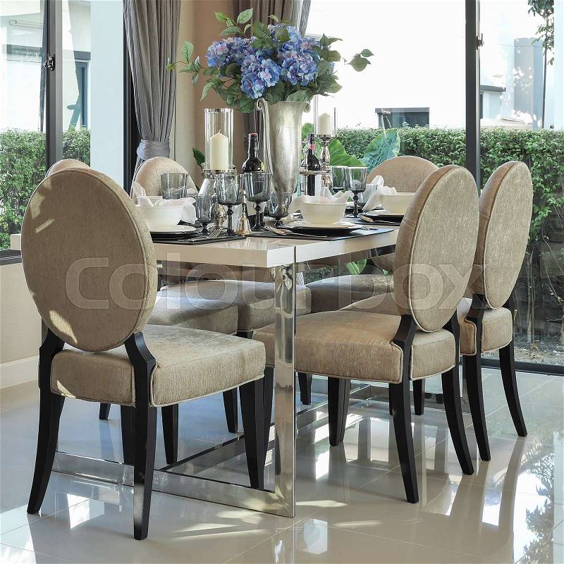 Modern dining table and comfortable chairs with elegant table setting, stock photo