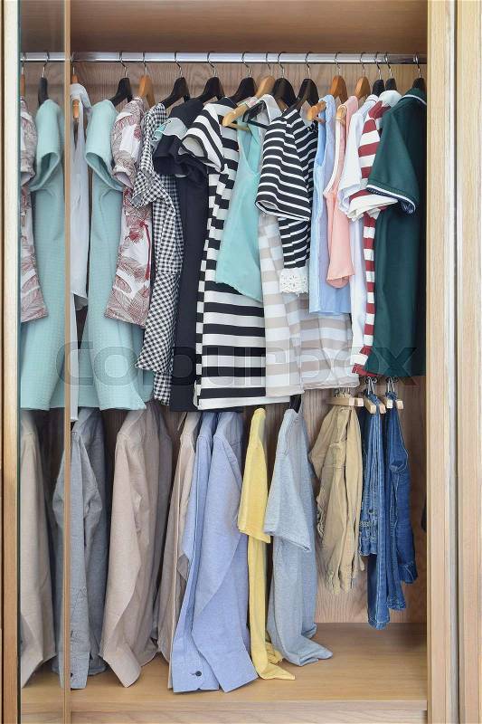 Colorful clothes hanging in wardrobe, stock photo