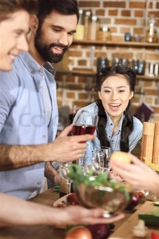 Young people partying, eating and drinking wine at home party, stock photo