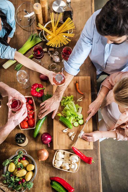 Young people eating, drinking wine at home party, stock photo