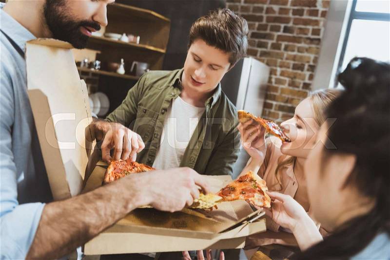 Young people partying, eating pizza at home party, stock photo