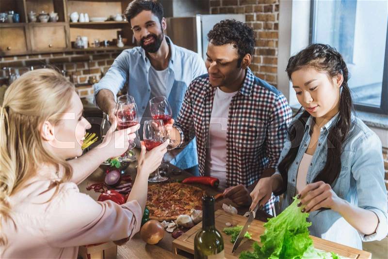 Young people partying, eating pizza and drinking wine at home party, stock photo