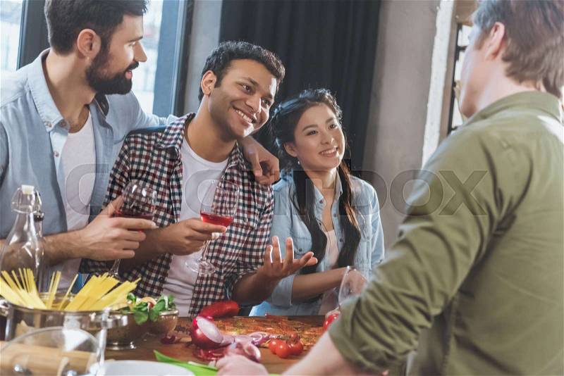Young people partying, eating pizza and drinking wine at home party, stock photo