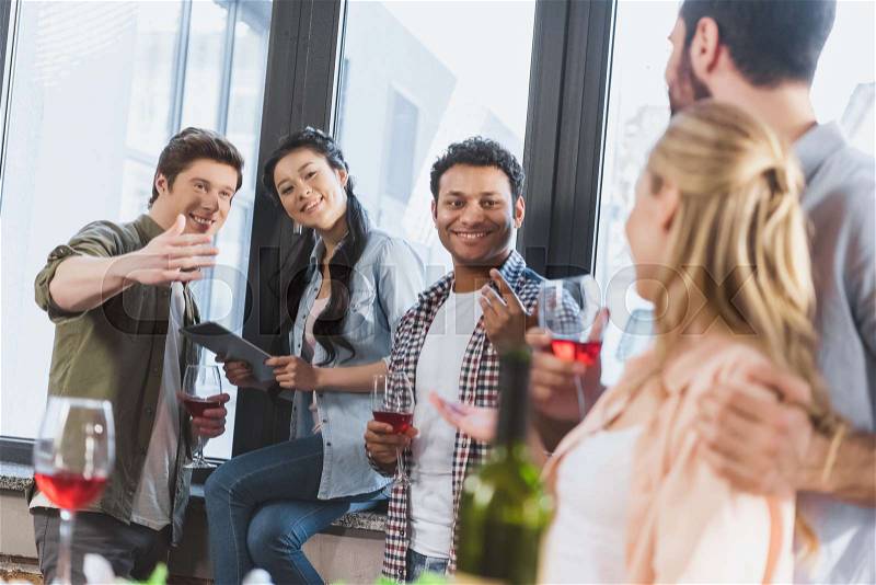 Young people partying, drinking wine at home party, stock photo