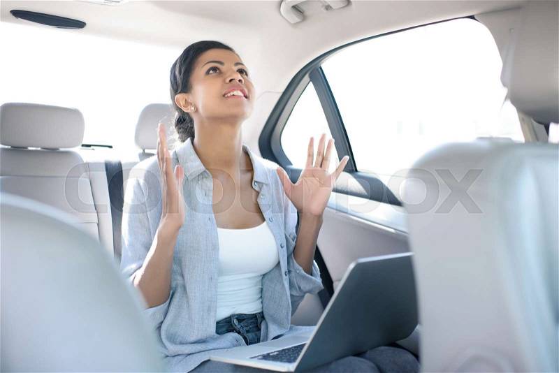 Angry african american woman working with laptop in taxi , stock photo