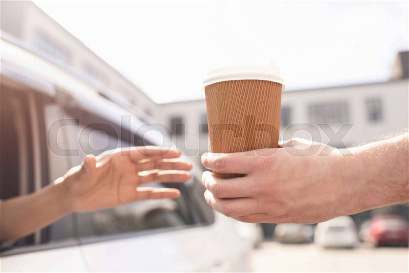 Partial view of woman sitting in car and buying coffee to go, stock photo