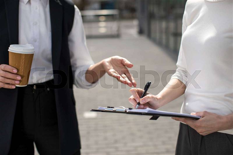 Cropped view of two businesswomen on meeting outdoors near office building, stock photo