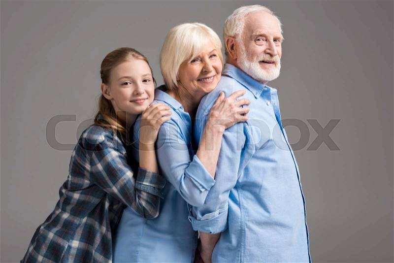 Happy family hugging and looking at camera isolated on grey in studio, stock photo