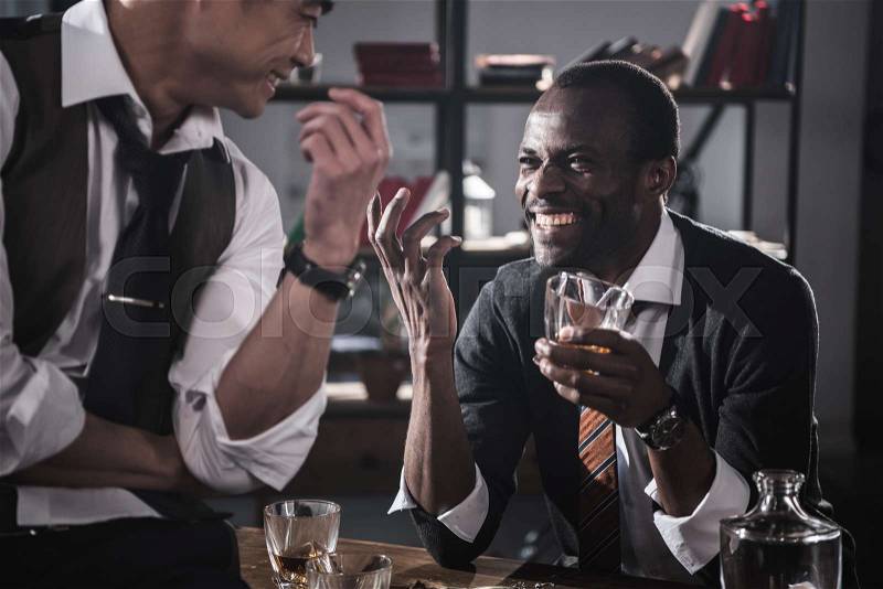 Cheerful colleagues drinking alcohol while spending time together after work, stock photo