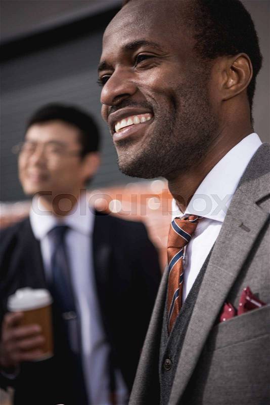Young smiling multiethnic businessmen meeting at coffee break outdoors, business team meeting, stock photo