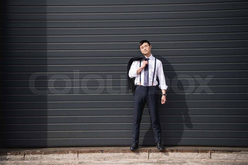 Young confident asian businessman standing outdoors with copy space, stock photo