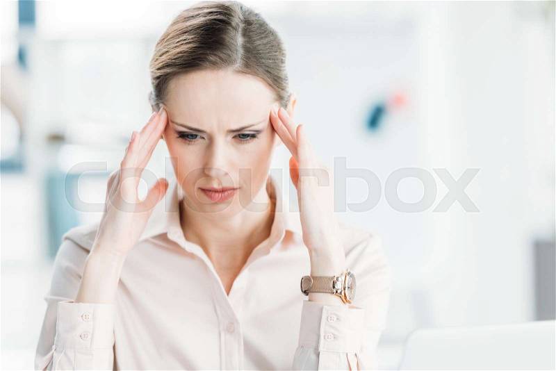 Portrait of tired pensive businesswoman with hands on head looking down, stock photo