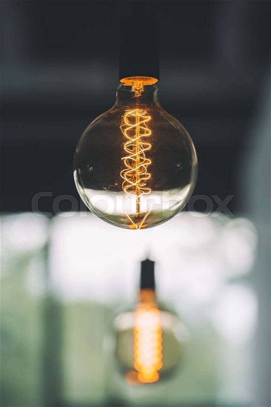 Vintage edison light bulb hanging with other light bulbs indoors with copy space, stock photo