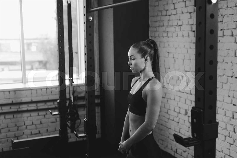 Attractive sportswoman standing in sports center, black and white, stock photo