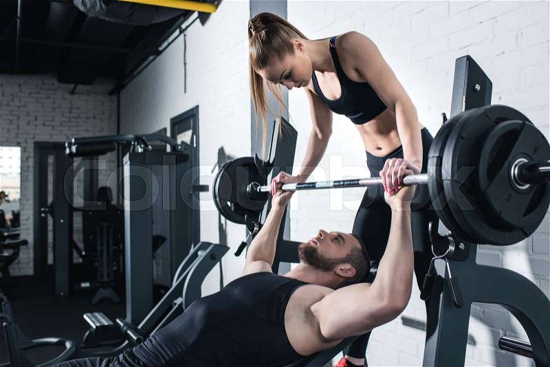 Athletic young man and woman training with dumbbell in gym , stock photo