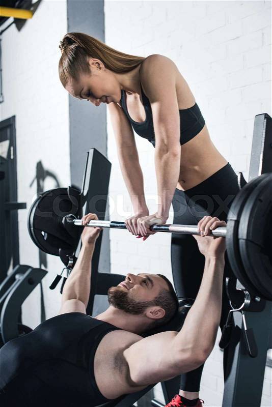 Athletic young man and woman training with dumbbell in gym , stock photo