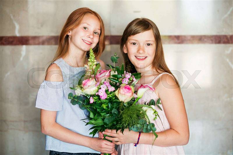 Two sweet little girls with beautiful flower bouquet, stock photo