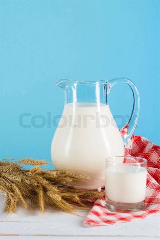 Close-up view of fresh organic milk and wheat ears on wooden table top, stock photo