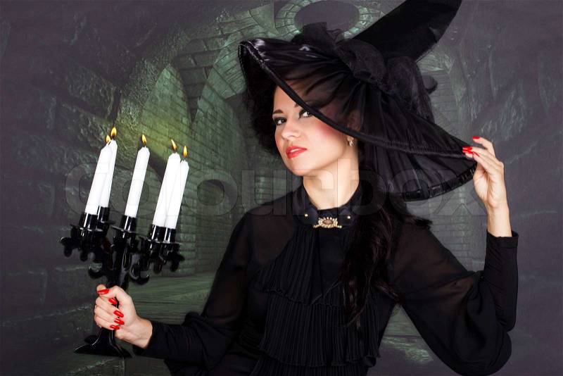 Sexy witch with the candles in the dark castle, stock photo