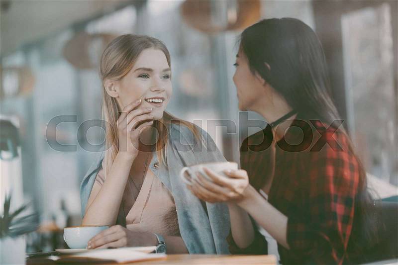 Young attractive multicultural women on coffee break in cafe, stock photo