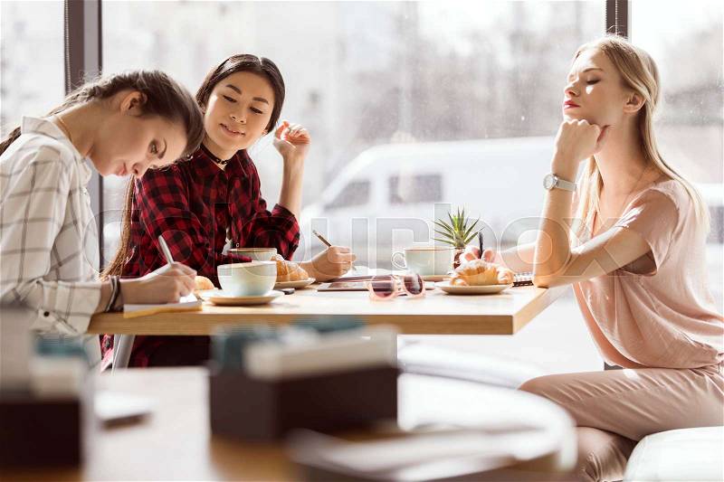 Side view of group of friends study together in cafe, stock photo
