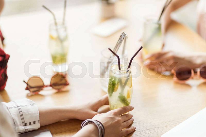 Young girls drinking cocktails together while sitting at table in cafe, having lunch, stock photo