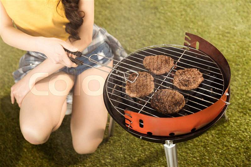 Cropped shot of woman preparing barbecue grill outdoors, stock photo