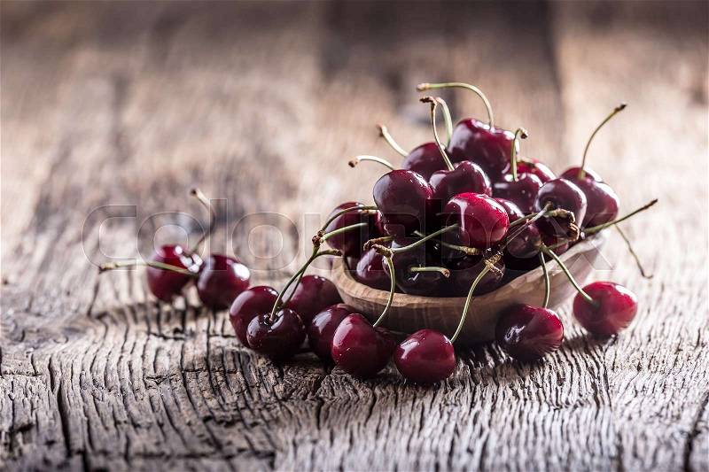 Cherries. Fresh sweet cherries. Delicious cherries with water drops in retro bowl on old oak table, stock photo