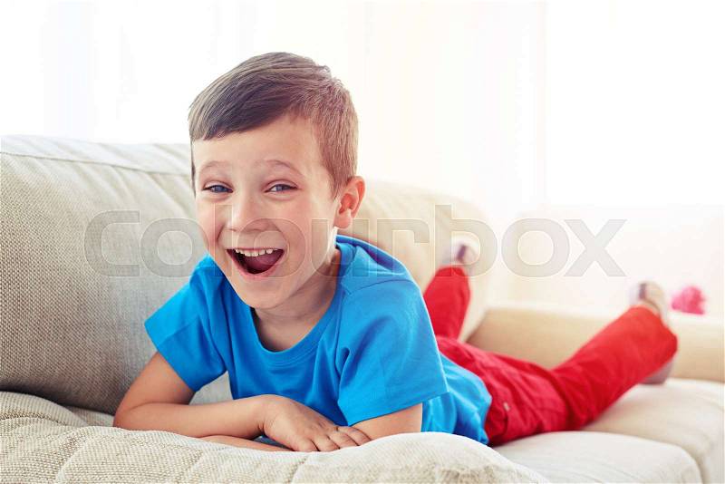 Close-up shot of surprised small boy lying on the sofa. Small child relaxing on the settee in the living room , stock photo