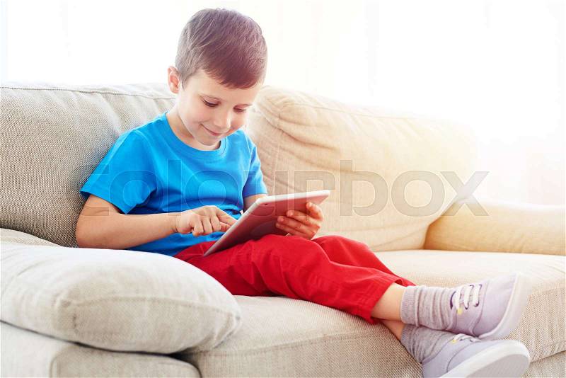 Close-up shot of small boy looking and touching a screen of a tablet, stock photo