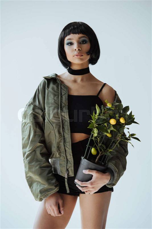 Beautiful stylish african american girl with bobbed hair holding small lemon tree in pot, stock photo