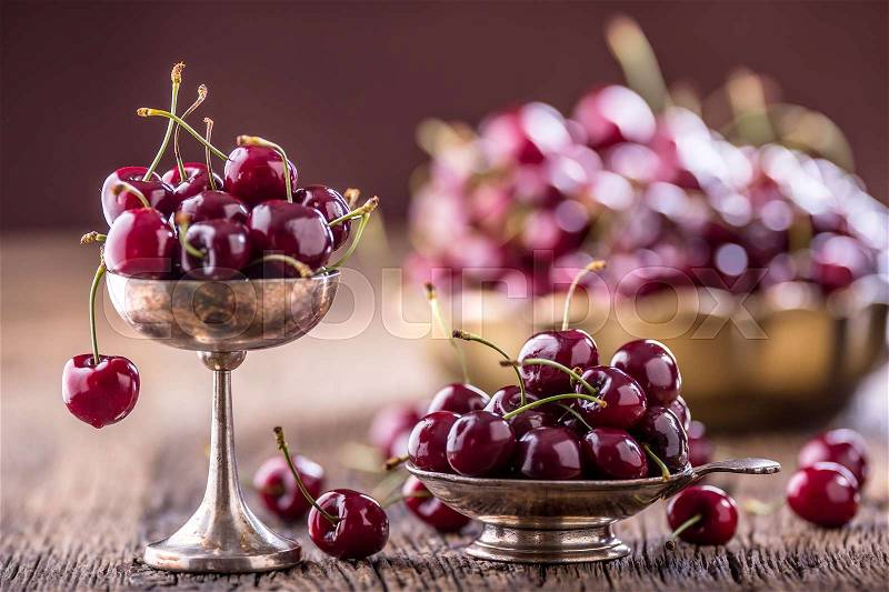Cherries. Fresh sweet cherries. Delicious cherries with water drops in retro bowl on old oak table, stock photo