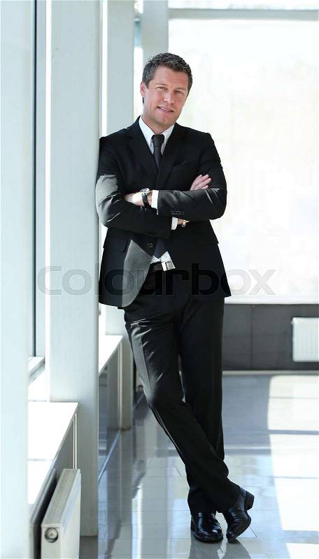 Full length of a business man with crossed arms in the modern office, stock photo