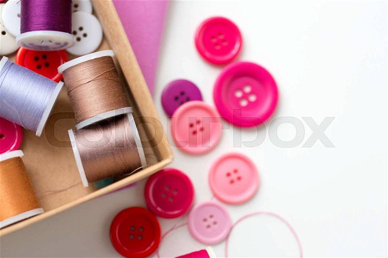 Needlework, craft, sewing and tailoring concept - box with thread spools and buttons on table, stock photo