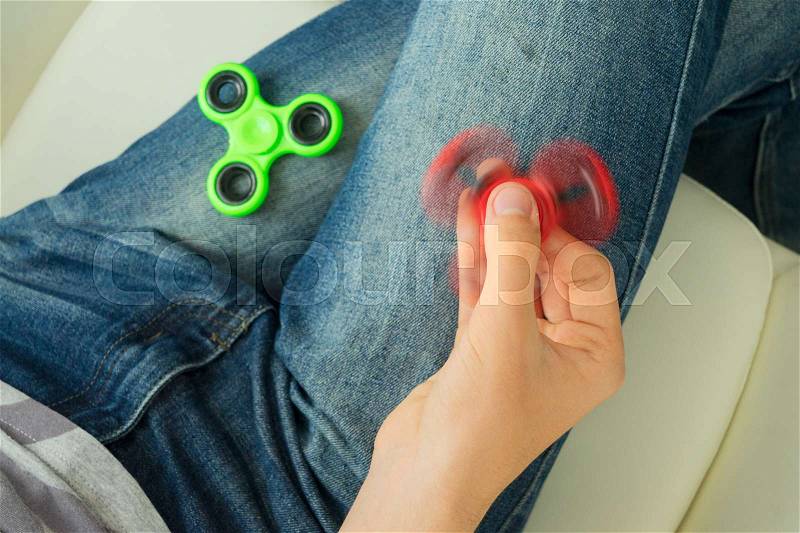 Trendy fidget spinner - someone holding spinning fidget spinner in hand, close up view, stock photo