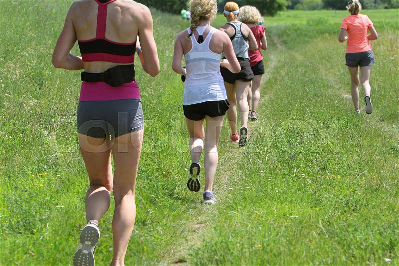 Outdoor cross-country running, group of young active people running in nature , stock photo