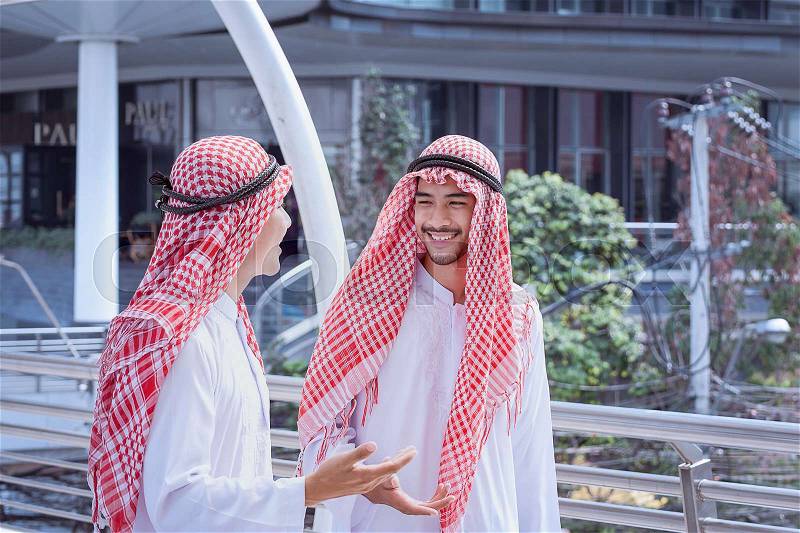 Two arabian business men discuss and walk together around modern city, stock photo