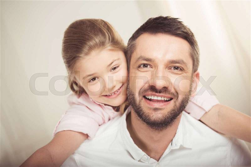 Close-up portrait of happy father and daughter hugging and smiling at camera, stock photo